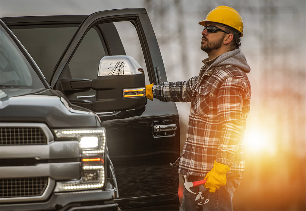 A guy in a hard hat opening the door to his black truck