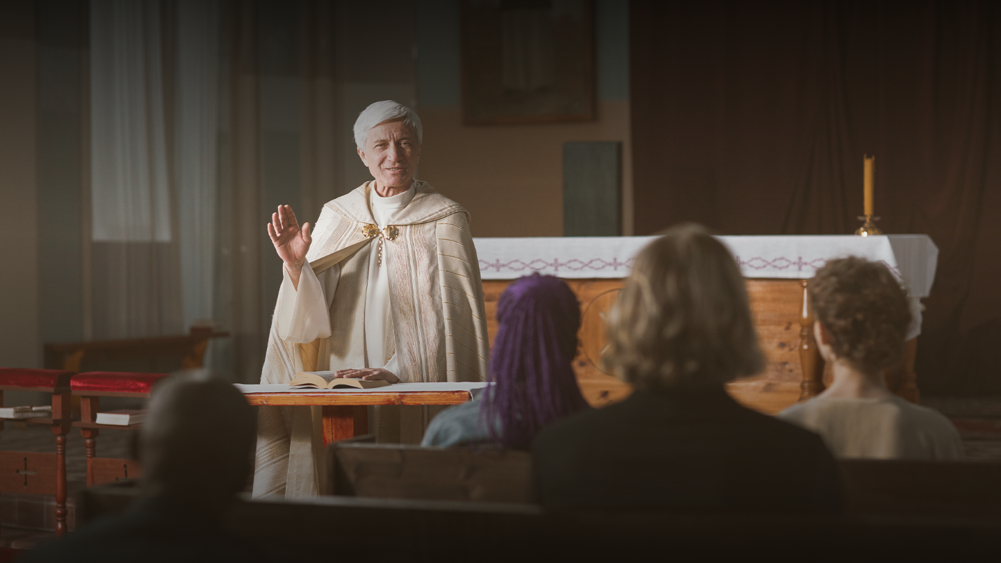 A Catholic priest at the altar preaching to his congregation sitting in the pews.